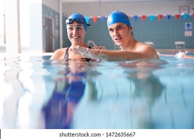 Male Swimming Teacher Giving Woman One To One Lesson In Pool