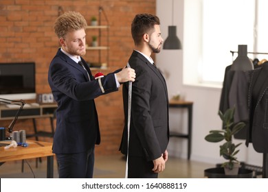 Male tailor taking client's measurements in atelier