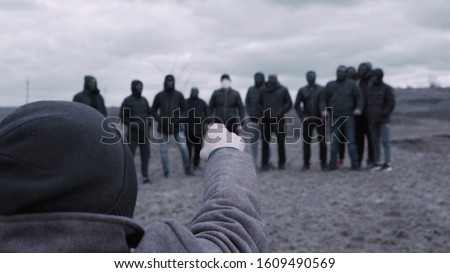 Male is talking to gang. Footage. Man gives speech to entire gang of gangsters in black jackets and masks. Criminal grouping with its own rules
