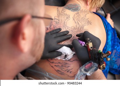 Male Tattoo Artist Draws A Design On Back Of Client
