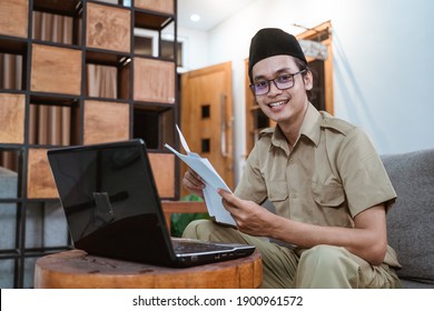 male teacher in civil servant smile looking at camera when working from home using laptop computer sitting on the sofa at home