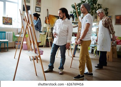 Male Teacher Consulting One Of His Students In Art School