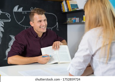 Male Teacher And Female Parent Having A Discussion In Classroom. Mom At Teacher Parent Meeting At Kindergarten.