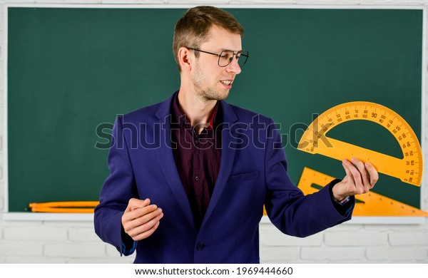 male teacher hold protractor. education and\
school concept. stem school disciplines. mathematics and people\
concept. man at blackboard. back to school. Maths and geometry.\
geometry favorite subject