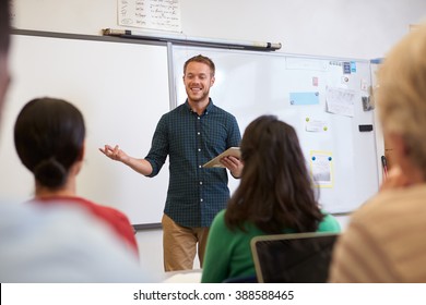 Male teacher listening to students at adult education class