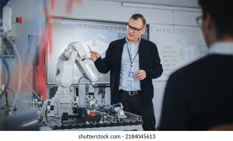 Male Teacher Talking With Students At University Robotics Class At University. Bionic Claw Is Moving Under Supervision Of The Lector. Computer Science Education And Learning Concept.