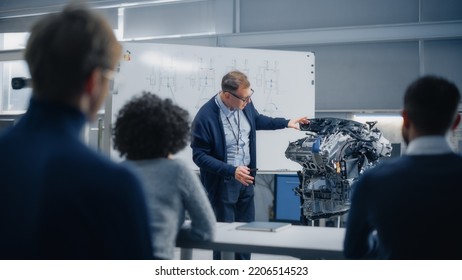 Male Teacher Talks About Engineering To Students And Points At Whiteboard. Smart Future Scientists Listen Attentively And Look At Engine. Industry 4 Sustainable Energy Research And Education Concept.