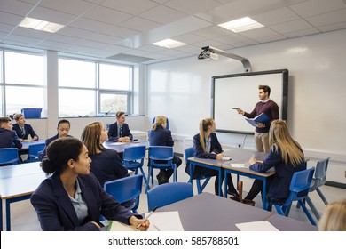 Male teacher is teaching a group of teenagers in a high school lesson. - Shutterstock ID 585788501
