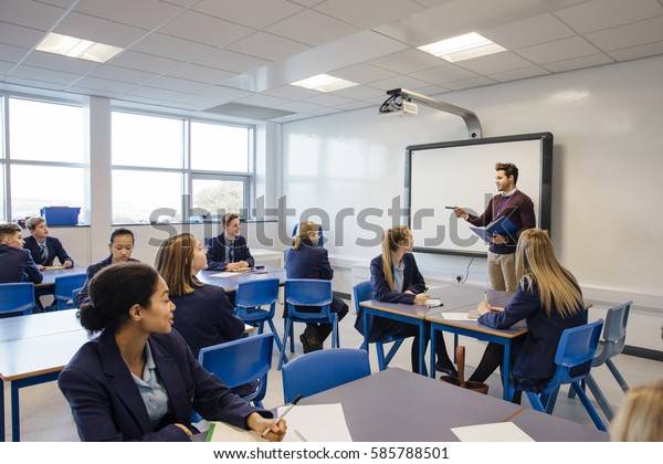 Male teacher is teaching a group of teenagers in\
a high school lesson.