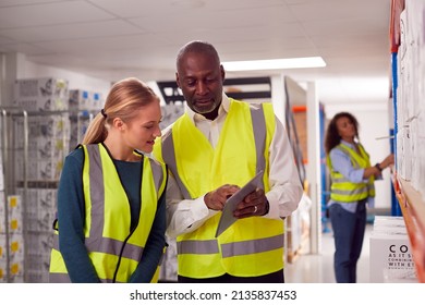 Male Team Leader With Digital Tablet In Warehouse Training Intern Standing By Shelves