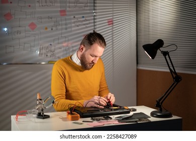 Male tech tests electronic equipment repairing laptop computer in service centre using multimeter. Copy space - Shutterstock ID 2258427089