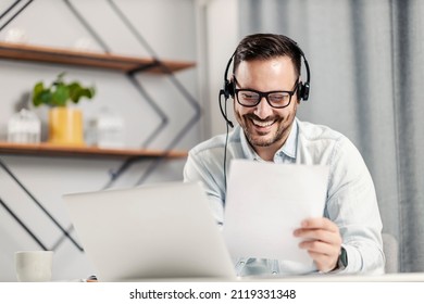 A Male Technical Support Agent Holding Paperwork And Having A Video Call At Home Office.