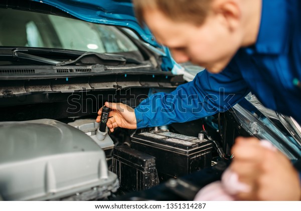 Male\
technician checks brake fluid level in\
car