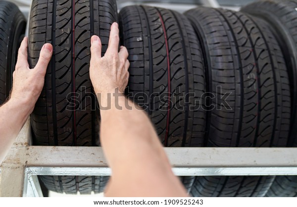 Male technician hand select\
one tire of shelf list in auto car service garage for customer\
choose