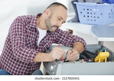 Male Technician Inspecting And Fixing A Washer And Dryer