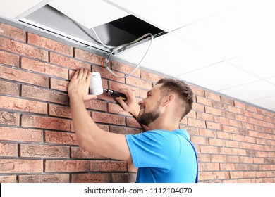 Male Technician Installing Alarm System Indoors