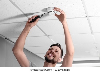 Male Technician Installing Smoke Alarm System Indoors