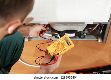 Male Technician Repairing Broken Refrigerator Indoors, Closeup