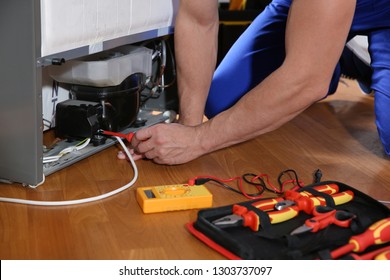 Male Technician Repairing Broken Refrigerator Indoors, Closeup