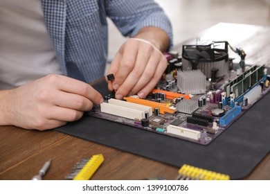 Male technician repairing motherboard at table, closeup - Shutterstock ID 1399100786