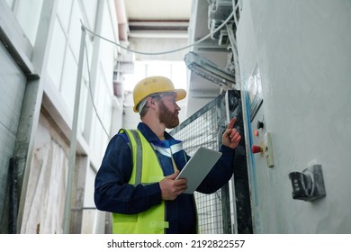 Male Technician With Tablet Switching Production Equipment In Factory While Going To Press Start Button On Panel During Work