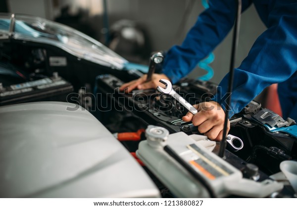 Male technician works\
with car engine