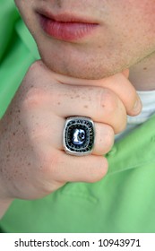 Male Teen Displays His Championship Baseball Ring.  He Is Wearing A Light Green Polo.