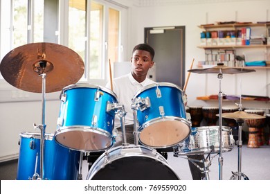 Male Teenage Pupil Playing Drums In Music Lesson