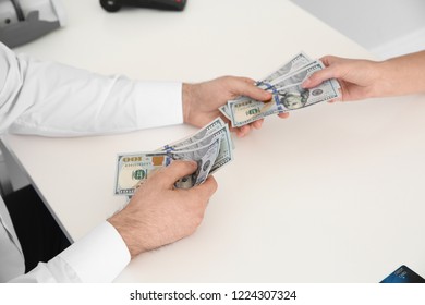 Male Teller Giving Money To Woman At Table, Closeup