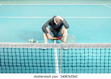 Male Tennis Player Sitting On The Court. Athlete Holding A Racket. Sportsman Has Adjusted, Lost And Holds His Head