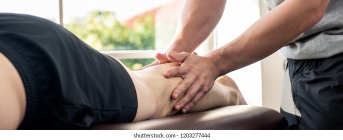 Male Therapist Giving Leg Massage To Athlete Patient On The Bed In Clinic For Sports Physical Therapy Concept, Panoramic Banner