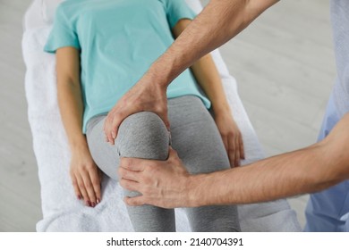 Male therapist massaging knee of female patient during physiotherapy session at the hospital. Close up of woman's knee lying on medical couch. Concept of osteopathy and chiropractic leg adjustment. - Powered by Shutterstock