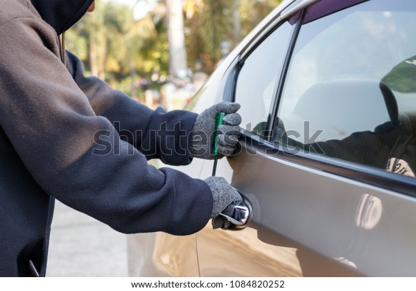 Male thief\
tries to steal a car. Car theft\
concept