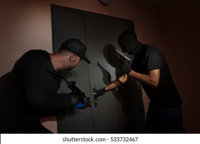 Male Thieves Opening Metal Door