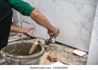 Male tiler using trowel laying marble tile with cement in bathroom. Housing development, Interior improvement renovation