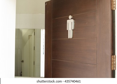 Male Toilet Sign On Wooden Door.