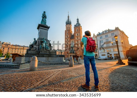 Male tourist with backpack photographing famous Polish basilica in the center of Krakow