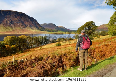 Male tourist enjoying the view of Crummock Water lake, located between Loweswater and Buttermere, in the Lake District in Cumbria, North West England.