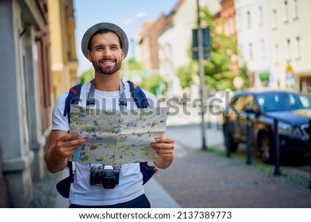 Male tourist with map in visiting European city in summer.Young man exlporing city