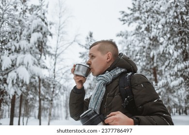 male tourist pours hot tea from a thermos in the winter on the street. Winter hiking concept, camping, travel. close-up - Powered by Shutterstock