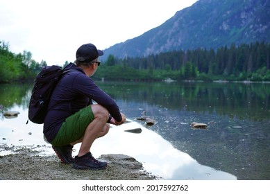 Male tourist sitting by the lake enjoying beautiful view in the mountains, Popradske mountain lake, Slovakia, High Tatras      