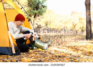 Male tourist with thermos sitting near tent in forest - Powered by Shutterstock