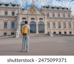 male tourist traveling in Austria, capital city Vienna. summer male solo trip to Europe, happy young man walking in park near Belvedere palace complex in Baroque style.
