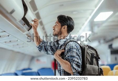 Male tourist traveling by plane Passengers place their carry-on luggage in lockers above their seats on the plane.