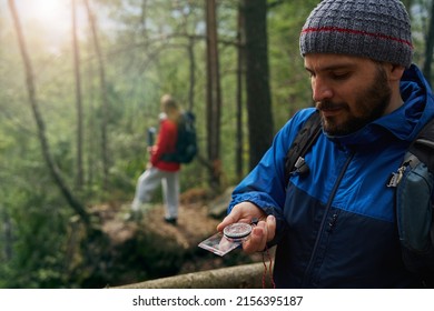 Male tourist using compass for navigation in forest - Powered by Shutterstock