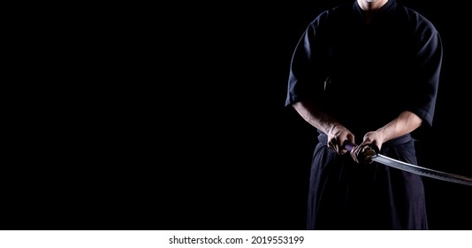 Male in tradition kendo armor with Samurai sword katana on black background. Shot in studio. Isolated with clipping path. Panoramic image.