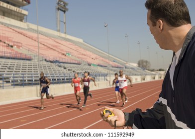 Male trainer measuring time while athletes racing - Powered by Shutterstock