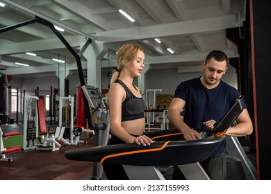 Male trainer talking to female client how work at  treadmill in fitness club.  Athlete Training in the Gym - Powered by Shutterstock