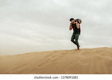 Male Training With Sandbag In The Desert