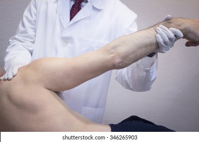 Male Traumatologist Orthopedics Surgeon Doctor Examining Middle Aged Man Patient To Determine Injury, Pain, Mobility And To Diagnose Medical Treatment In Shoulder, Arm, Elbow And Wrist.